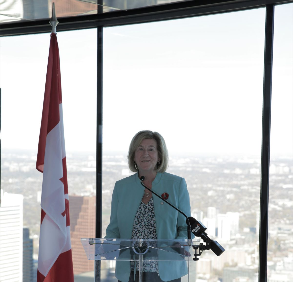 Flag and Minister Helena Jaczek at a podium