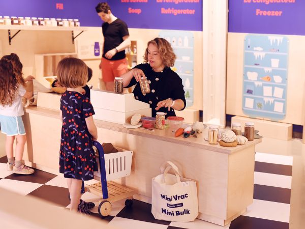 Participants stand at a lowered countertop in a makeshift grocery store in the Mini Mondo exhibit